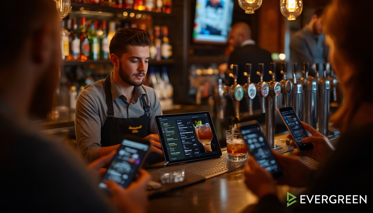bartender updating a digital beverage menu on a tablet while standing behind a modern bar
